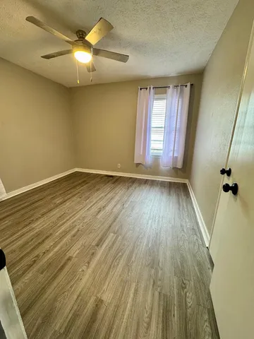 a view of empty room with wooden floor and fan