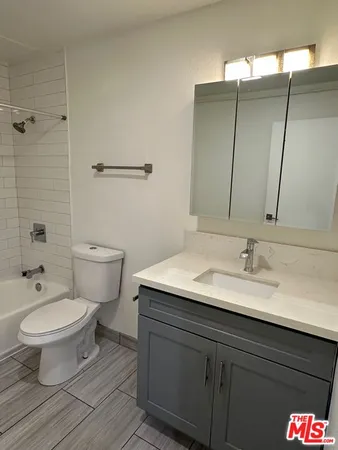 a bathroom with a granite countertop toilet a sink and a mirror