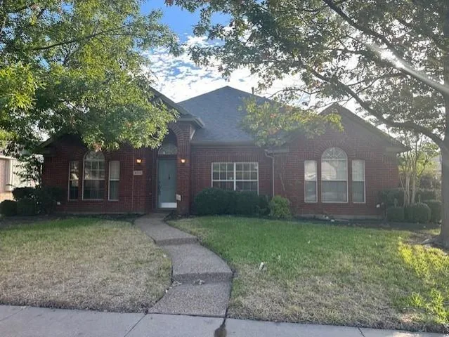 a brick house next to a yard with a large tree