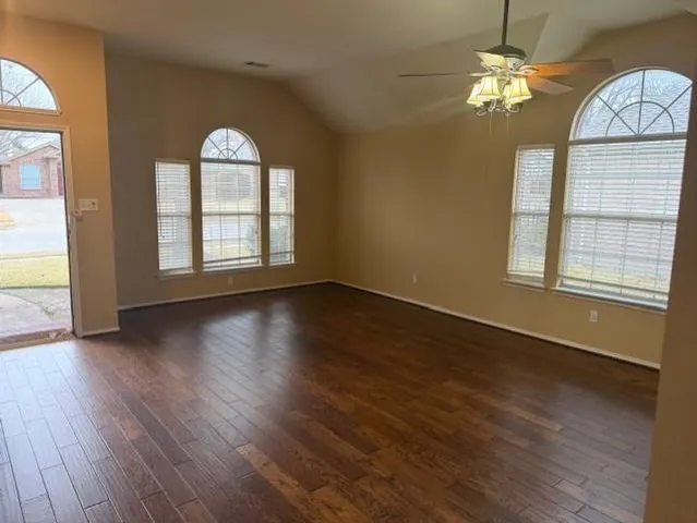 a view of an empty room with wooden floor and a window