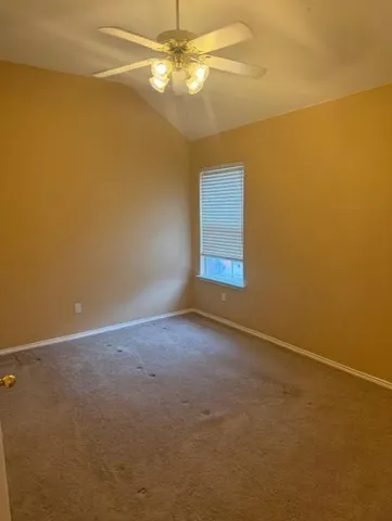 an empty room with a fan & a ceiling fan