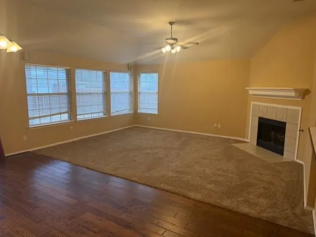 an empty room with wooden floor fireplace and windows