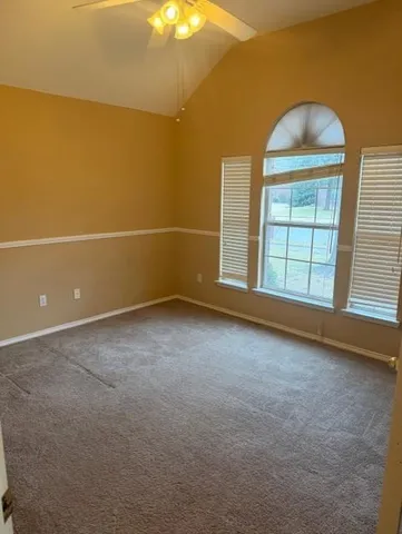 an empty room with windows and chandelier fan
