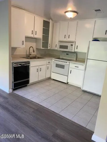 a kitchen with stainless steel appliances granite countertop a stove a sink and white cabinets