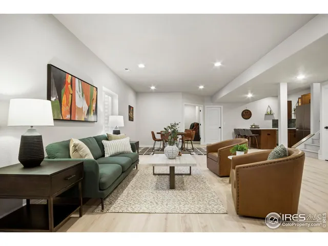 a kitchen with stainless steel appliances granite countertop a refrigerator a sink dishwasher a dining table and chairs with wooden floor