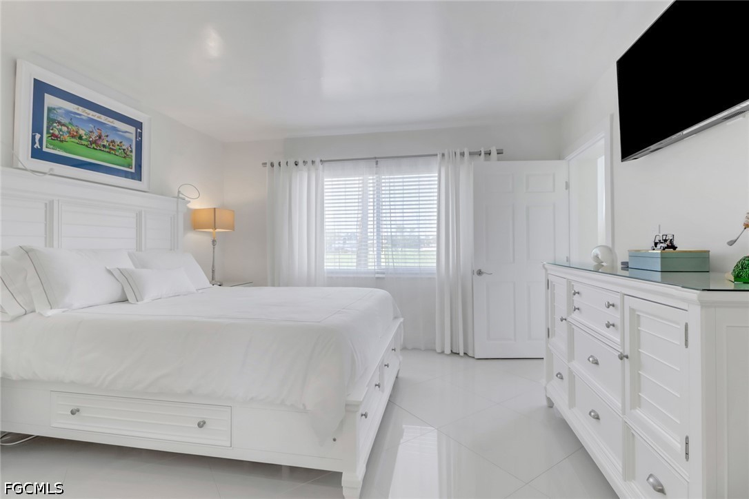 9 High Point Circle North, Unit 102 Naples, FL 34103 - Photo 16 of 48 a bedroom with a bed and a flat screen tv