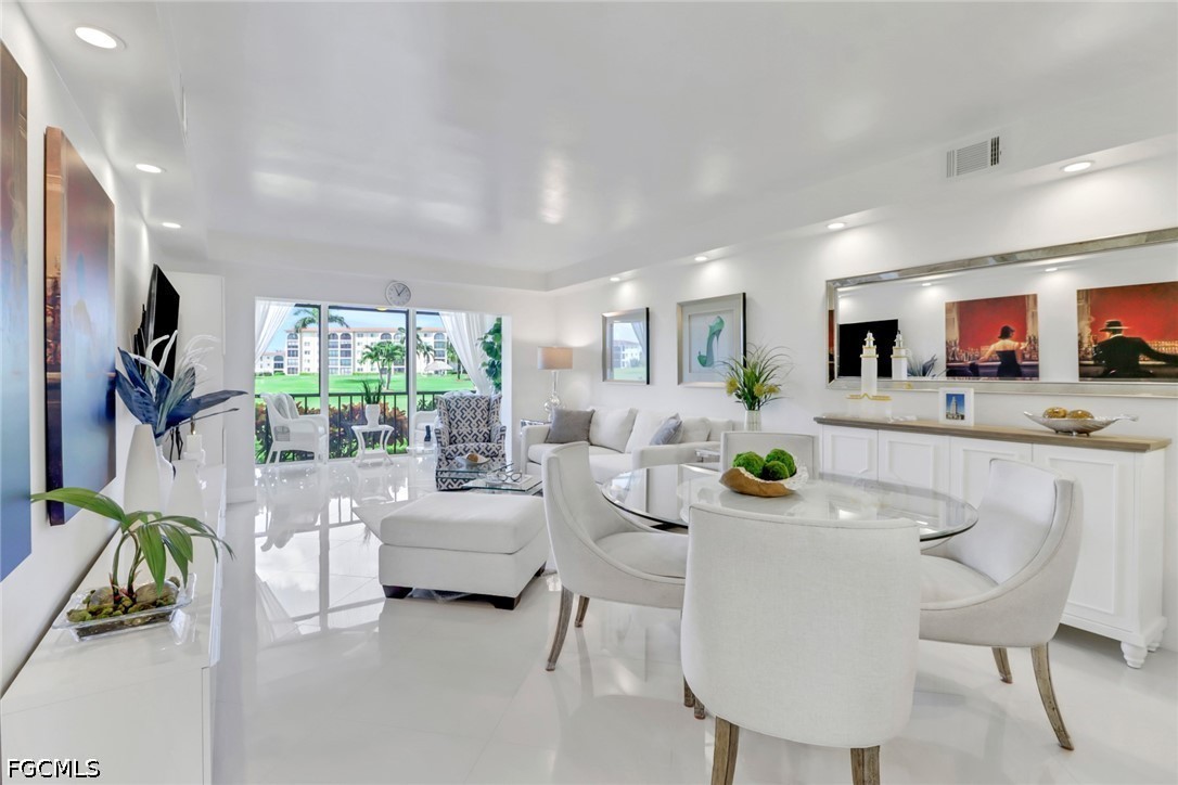 9 High Point Circle North, Unit 102 Naples, FL 34103 - Photo 2 of 48 a living room with furniture a chandelier and a dining table with kitchen view