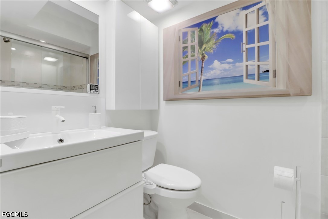 9 High Point Circle North, Unit 102 Naples, FL 34103 - Photo 23 of 48 a bathroom with a sink a mirror and a toilet