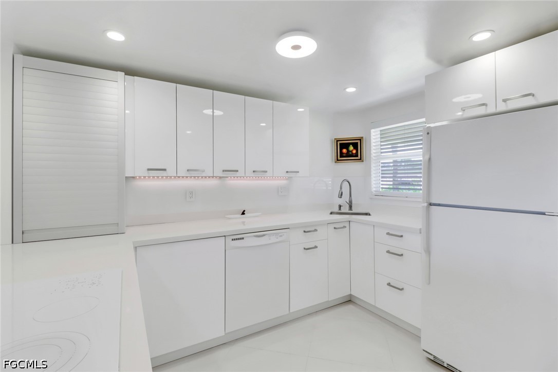 9 High Point Circle North, Unit 102 Naples, FL 34103 - Photo 6 of 48 a kitchen with white cabinets and sink