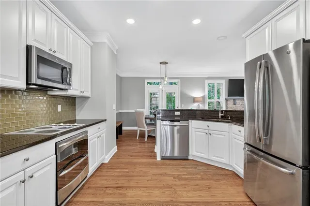 a kitchen with stainless steel appliances granite countertop a stove top oven a sink dishwasher a refrigerator and a microwave oven with wooden floor
