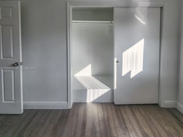 an empty room with wooden floor cabinet and windows