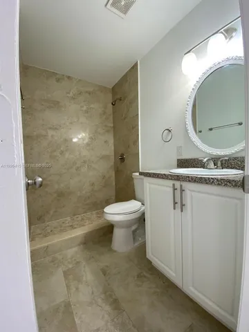 a bathroom with a granite countertop toilet a sink and a mirror
