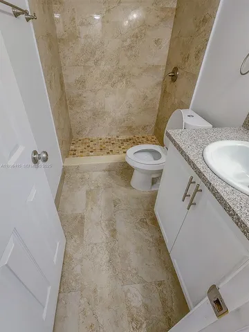 a bathroom with a granite countertop sink toilet and shower
