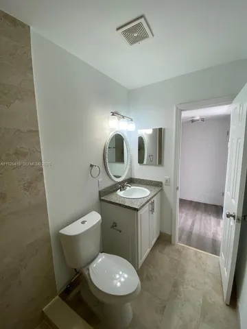 a bathroom with a granite countertop toilet sink and mirror