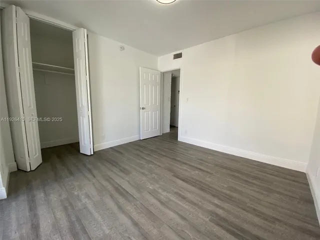an empty room with wooden floor and closet