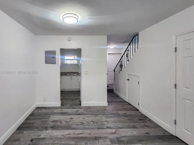 an empty room with wooden floor and staircase
