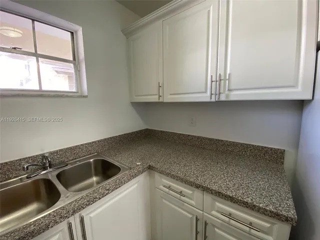 a kitchen with granite countertop white cabinets and a sink