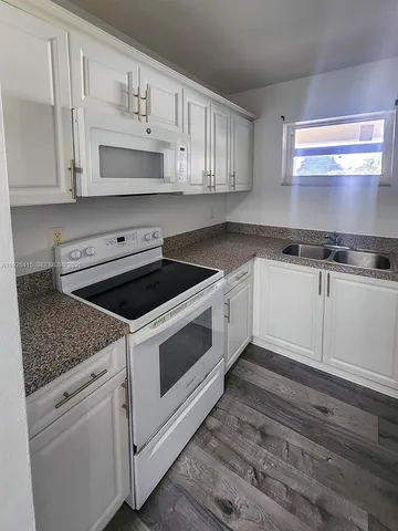 a kitchen with granite countertop white cabinets and white appliances