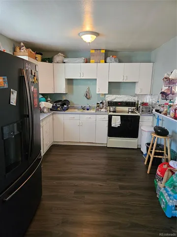 a kitchen with granite countertop a refrigerator stove and wooden floor