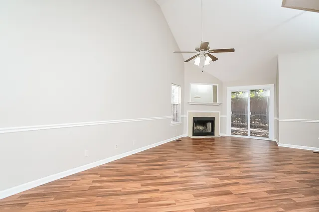a view of a livingroom with a fireplace a ceiling fan and wooden floor