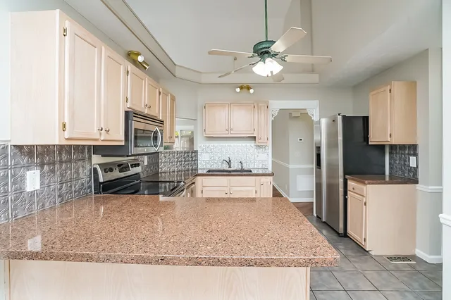 a large kitchen with kitchen island granite countertop a refrigerator a stove a sink and white cabinets with wooden floor