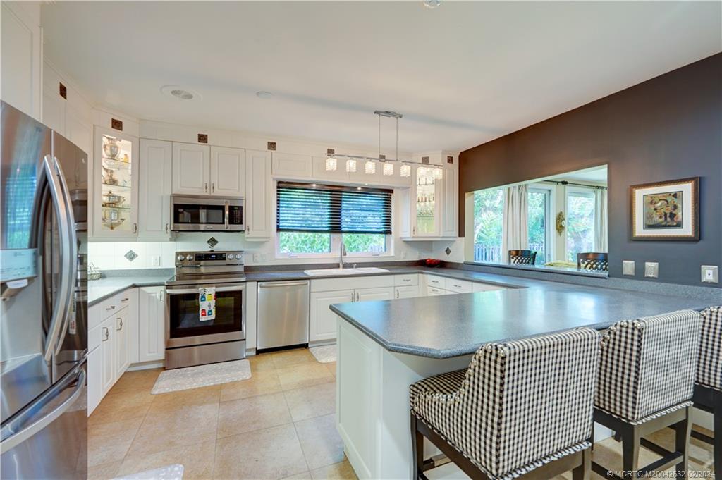132 South River Road Stuart, FL 34996 - Photo 8 of 45 a kitchen with stainless steel appliances granite countertop a sink a stove a refrigerator cabinets and a window