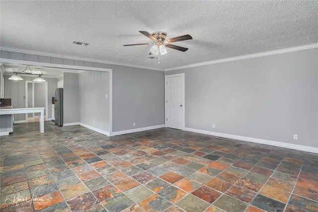 a view of a livingroom with a chandelier fan and kitchen view