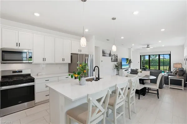 a kitchen with stainless steel appliances kitchen island granite countertop a refrigerator and a dining table