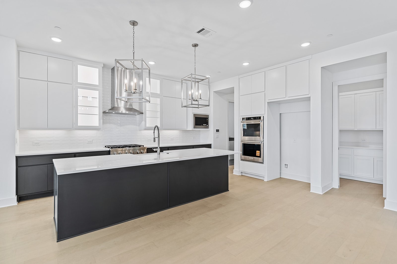 2385 Lineage Lane Leander, TX 78641 - Photo 6 of 36 a large kitchen with kitchen island a sink stainless steel appliances and a chandelier