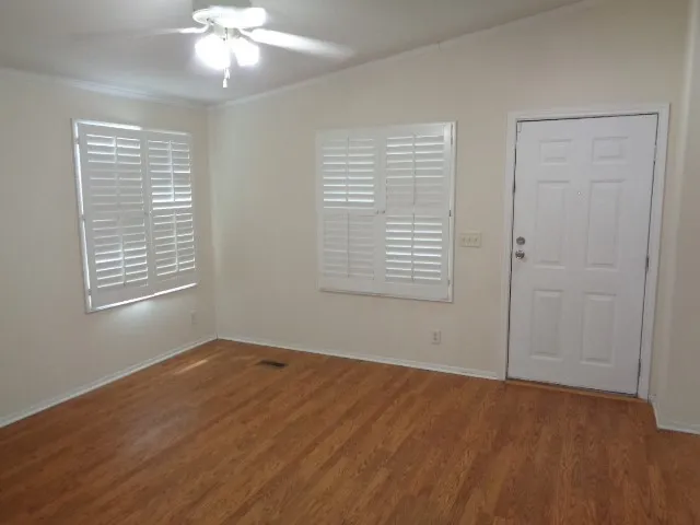 a view of an empty room with wooden floor and a window