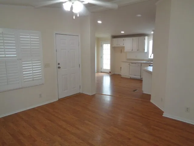 a view of a hallway with wooden floor and a kitchen