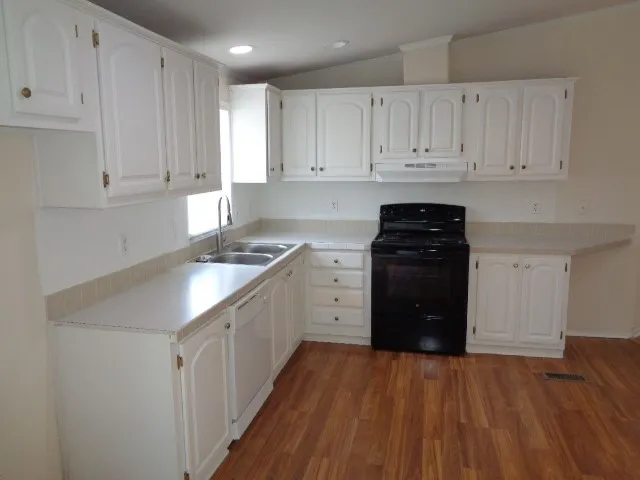 a kitchen with granite countertop white cabinets and appliances