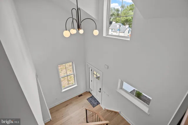 a picture of a room with wooden floor windows and a ceiling fan