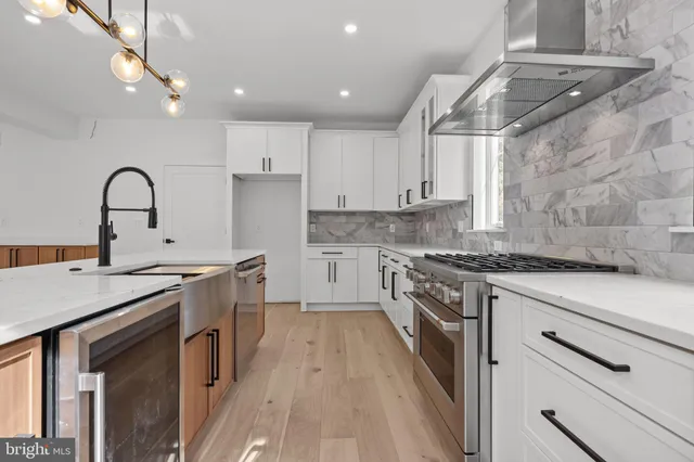 a kitchen with stainless steel appliances granite countertop a stove top oven a sink dishwasher and a refrigerator with wooden floor