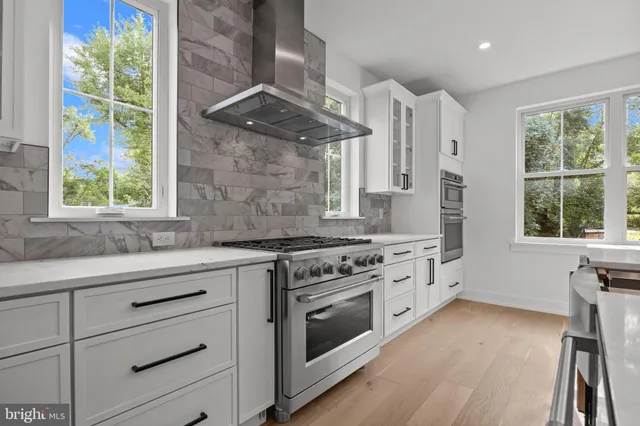 a kitchen with stainless steel appliances white cabinets and wooden floors