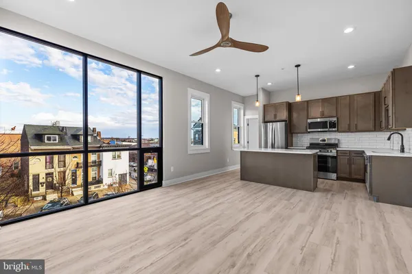 a large kitchen with stainless steel appliances kitchen island granite countertop a large kitchen island a stove a sink a refrigerator and a view of living room