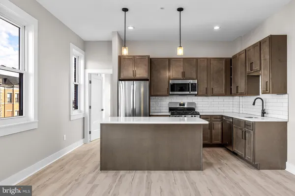 a large kitchen with stainless steel appliances granite countertop a stove a sink dishwasher a refrigerator and a microwave oven with wooden floor