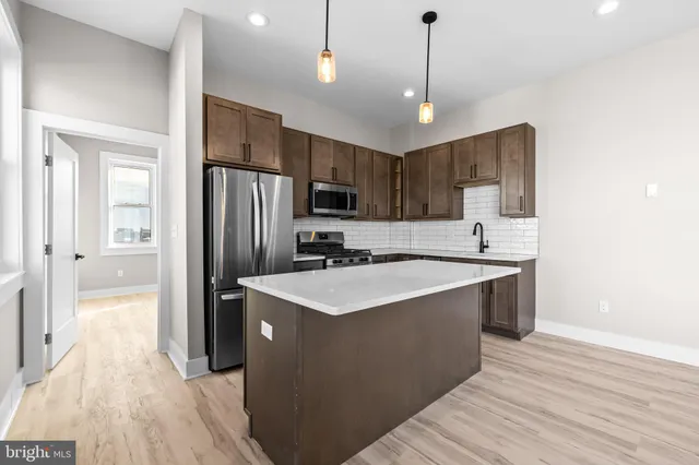a kitchen with kitchen island a sink stainless steel appliances and wooden floor
