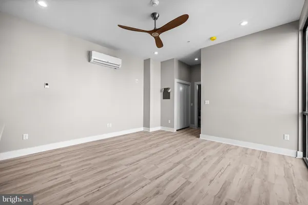 an empty room with wooden floor and a ceiling fan