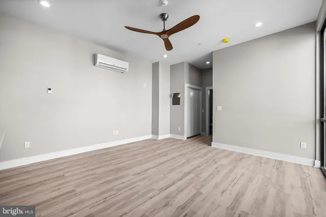 an empty room with wooden floor and a ceiling fan