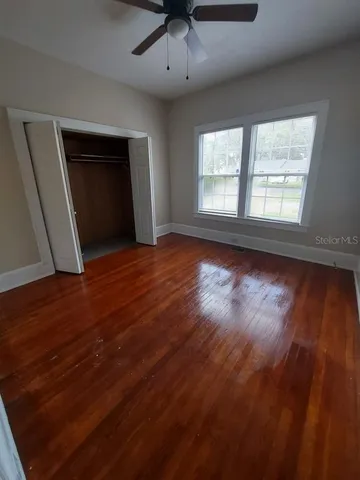 an empty room with wooden floor and windows