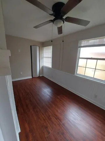 an empty room with wooden floor and windows