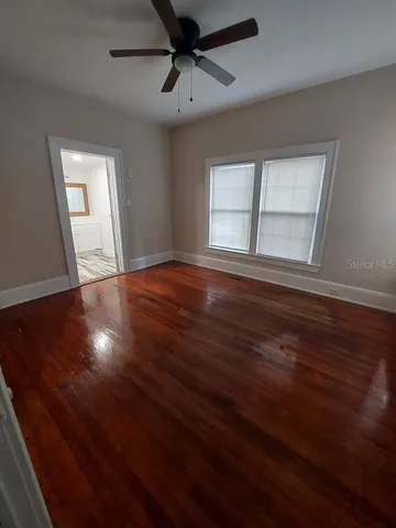 a view of an empty room with wooden floor and a window