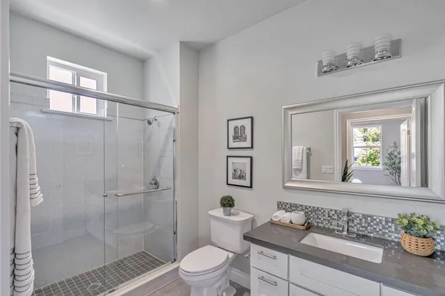 a bathroom with a granite countertop sink a toilet a mirror and shower