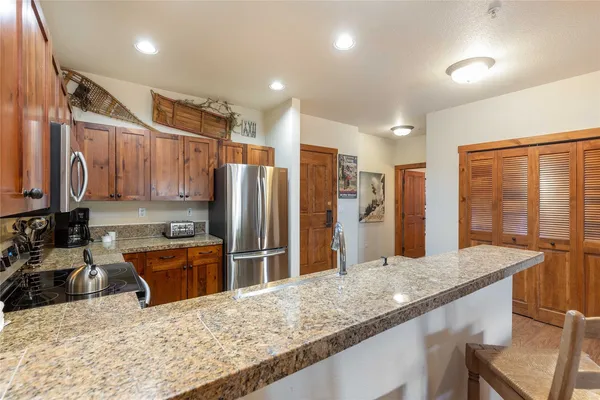 a kitchen with stainless steel appliances granite countertop a sink refrigerator and cabinets