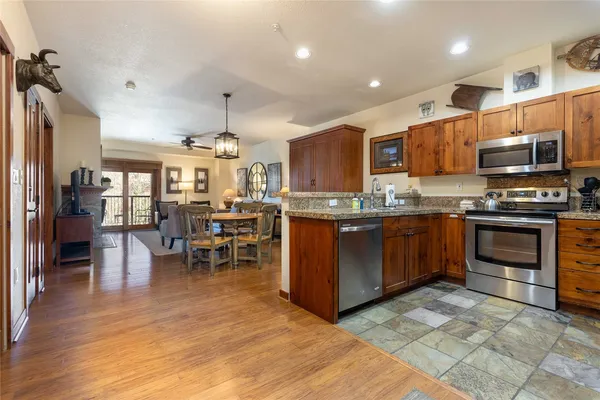 a kitchen with stainless steel appliances granite countertop a stove top oven a sink dishwasher a dining table and chairs