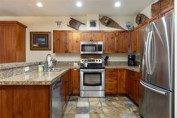 a kitchen with stainless steel appliances granite countertop a refrigerator a stove and a sink