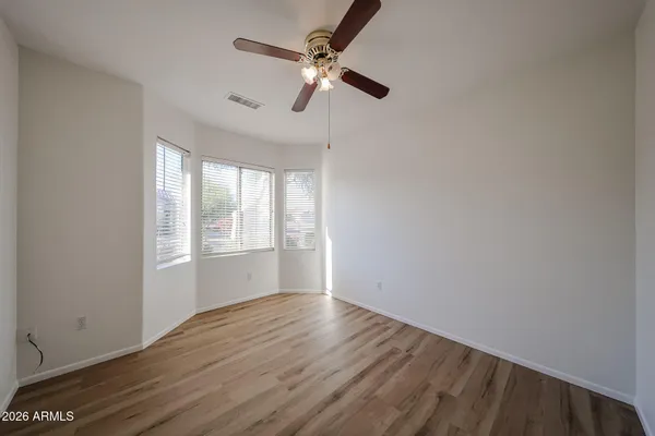a view of empty room with wooden floor and fan