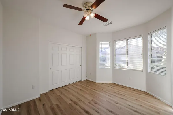 an empty room with wooden floor ceiling fan and window
