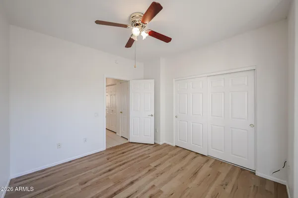 a view of empty room with wooden floor and fan